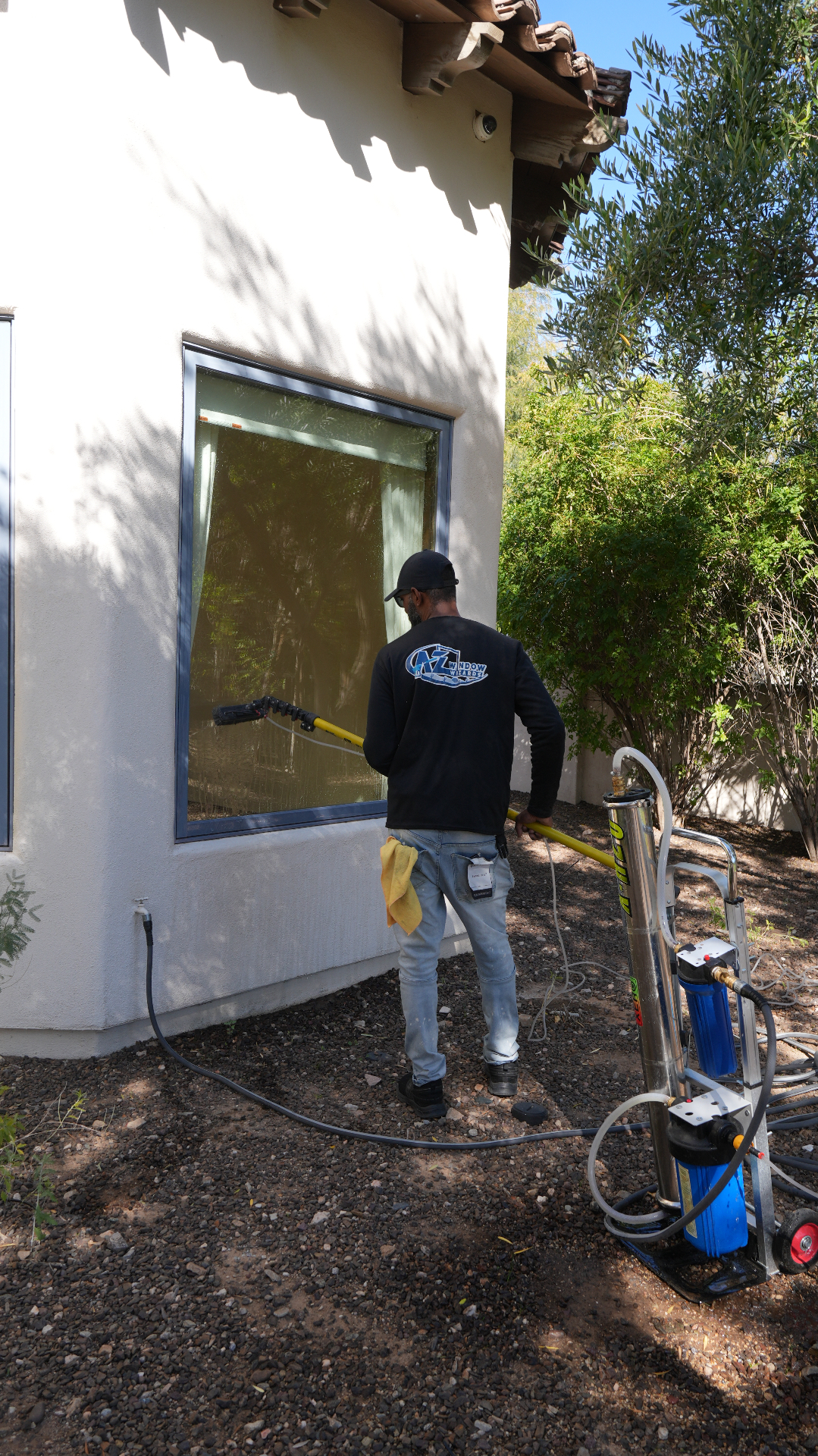 Window Wizards technician cleaning a large exterior window at an Arizona home